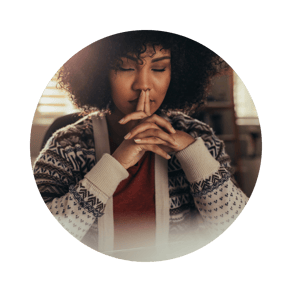 black woman with closed eyes crossed her hands in a meditation pose indoors