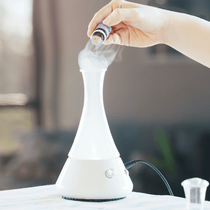 a person putting essential oil into a diffuser