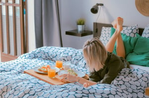 woman lying in bed having breakfast
